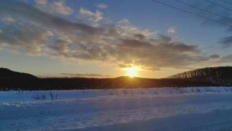 Conduciendo-Por-La-Puesta-De-Sol-Amarilla-Dorada-En-La-Carretera-Del-Paisaje-Invernal-Nevado-En-Hokkaido