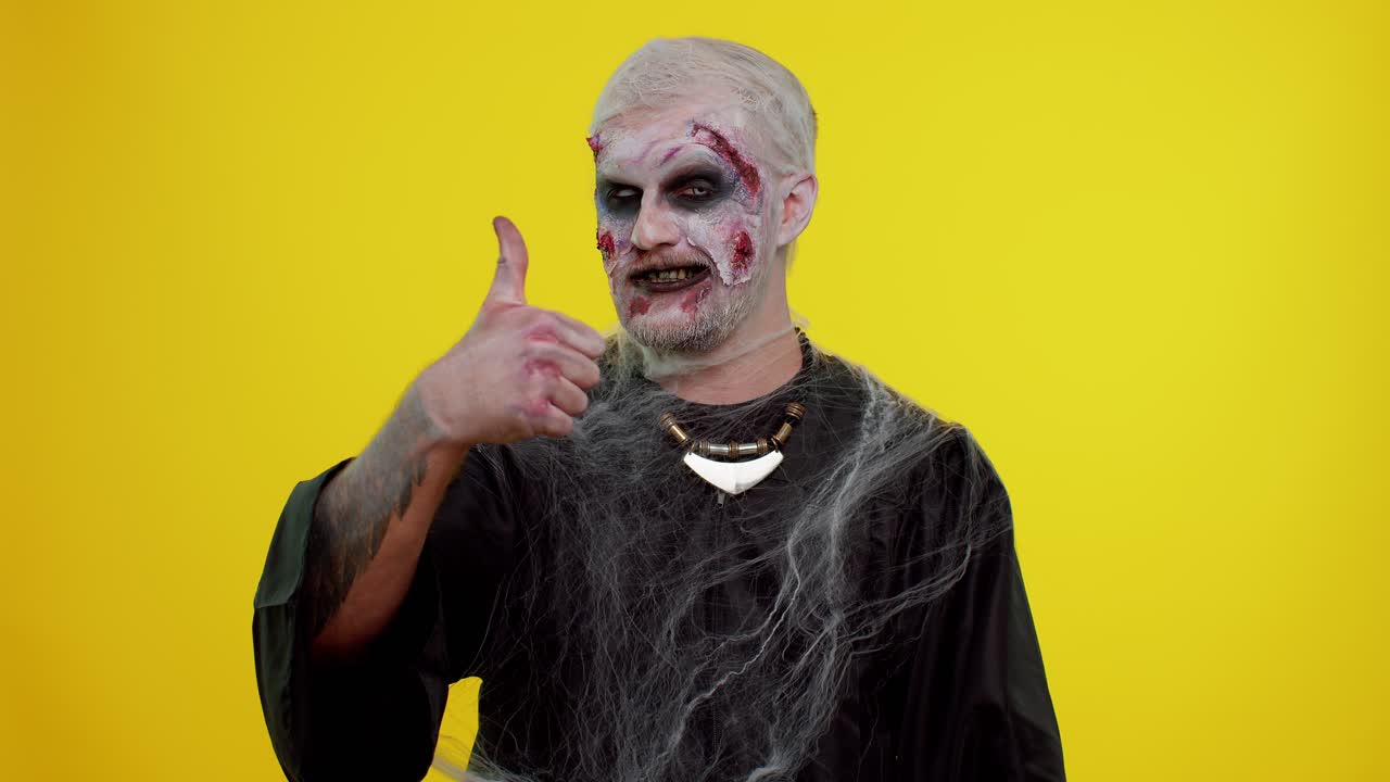 Uomo zombie sinistro di Halloween alza il pollice, concorda con qualcosa o dà una risposta positiva, approva.