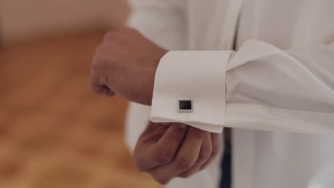 handsome groom man fixes his cuffs on a jacket with cufflinks. businessman