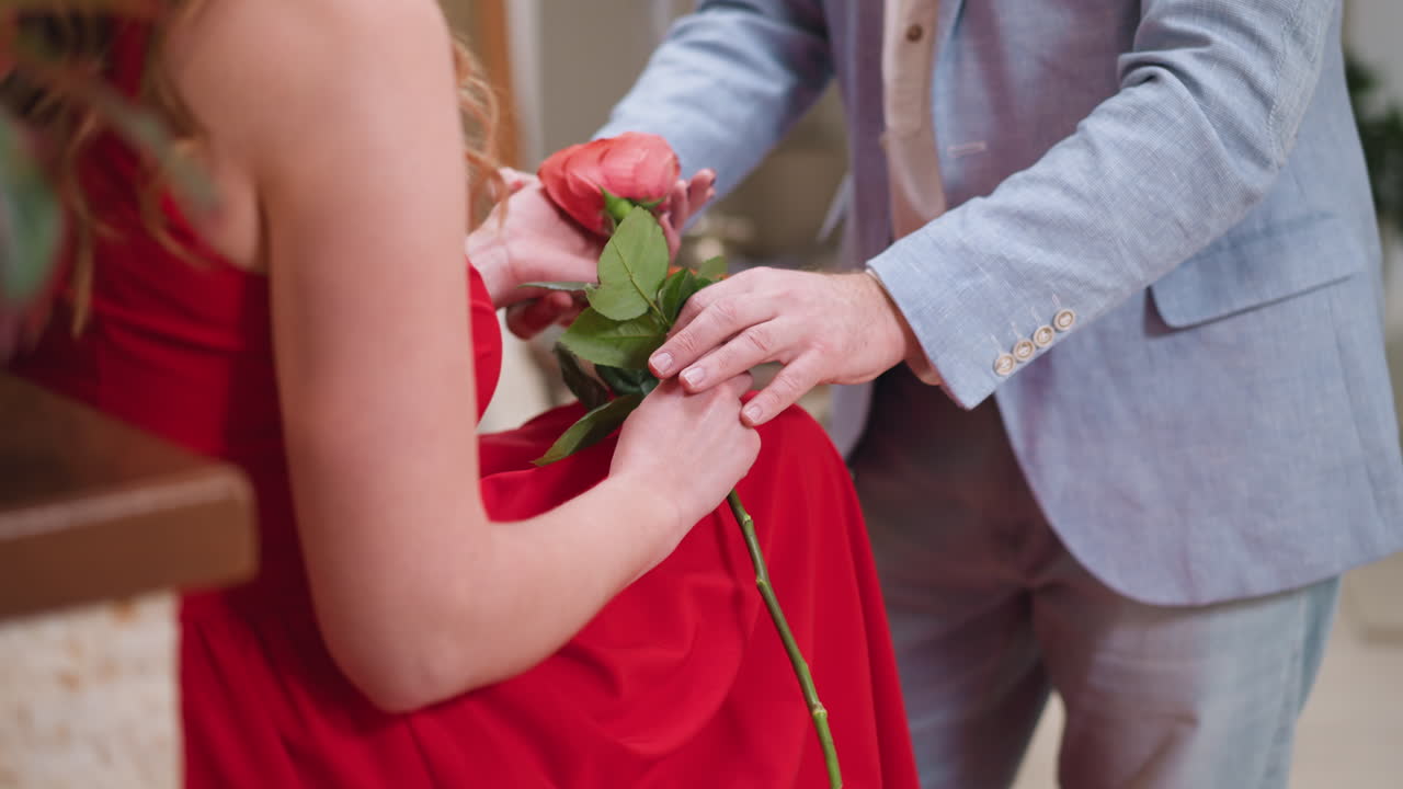 아티스트는 로즈와 함께 모델의 손을 조정합니다. 조심스러운 화가는 예술 작업실에서 여자의 그림을 위해 완벽한 포즈를 선택합니다. 창의적인 작업의 조직.