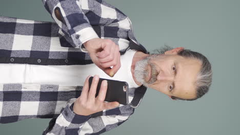 Vertical-video-of-The-old-man-who-likes-the-new-app.-Phone-app.