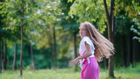 girl playing on the lawn. little girl dancing and having fun at the park