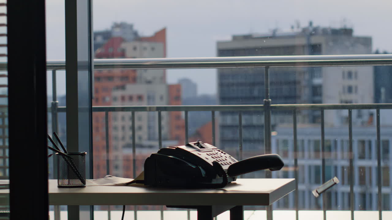 Man hitting landline phone using bat inside tall glass tower workplace closeup