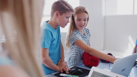 group of students in after school computer coding class learning to program robot vehicle
