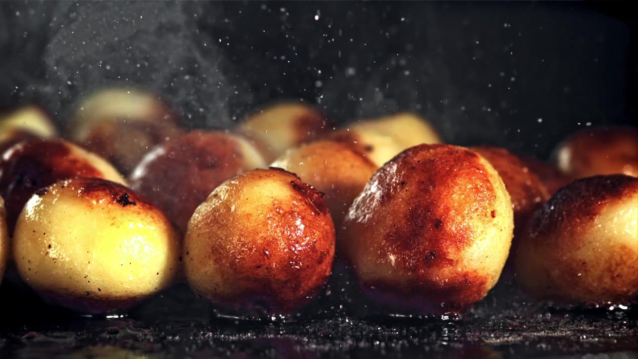 Close-up of Golden Potatoes Sizzling and Steaming on a Hot Surface