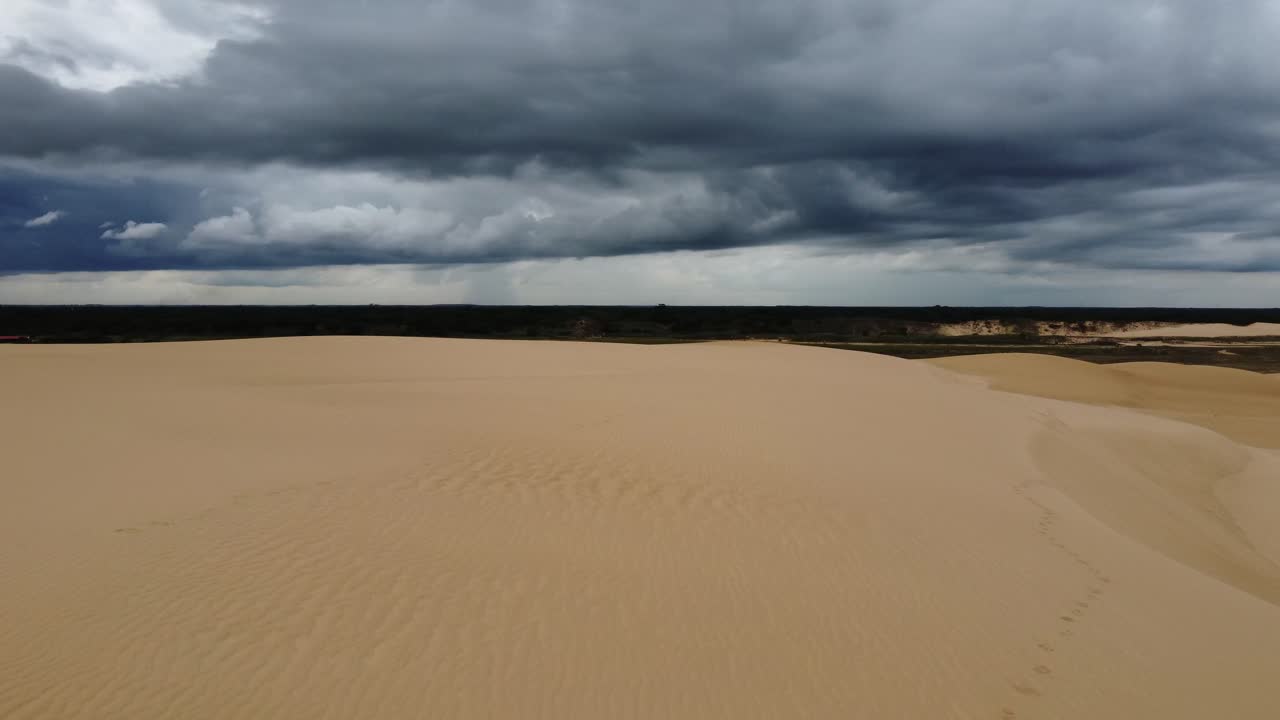 vuelo dramático bajo sobre una enorme duna de arena bajo un cielo oscuro y nublado