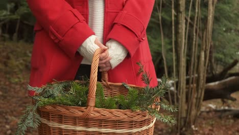 Frau-Im-Roten-Mantel,-Der-Einen-Korb-Voller-Immergrüner-Zweige-Für-Den-Kranz-Zeigt,-Der-Weihnachtszeit-Diy-4k-Zeitlupe-Macht