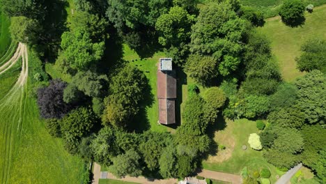 A-bird's-eye-view-pull-out-shot-of-Lady-Magdalene-church-in-Denton,-also-showing-surrounding-fields-and-trees