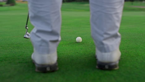 active golfer swing club on golf course. man legs stand on green grass fairway.