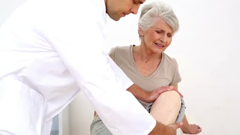 el paciente herido se estremece mientras el médico le toca la rodilla
