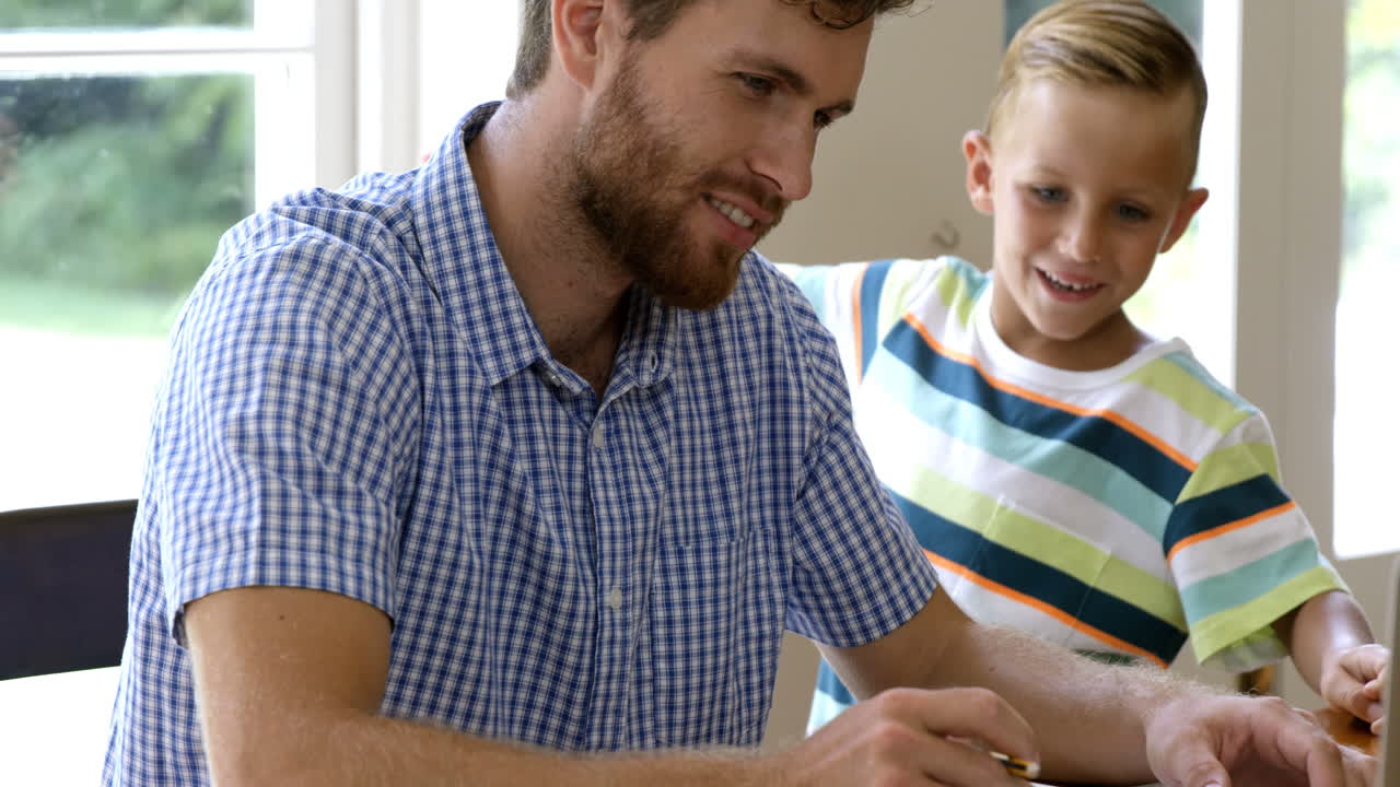 hijo abrazando a su padre mientras está trabajando en la computadora portátil