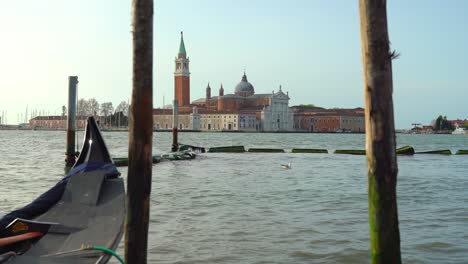 floating gondolas strapped to wooden pole in venice early in the morning with beautiful san giorgio maggiore church in the background