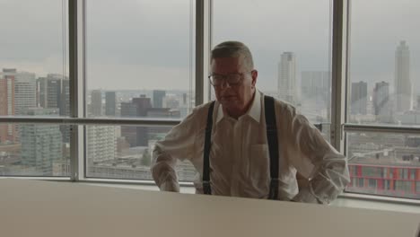 an older businessman angrily stands up from his chair and hits the board table in anger