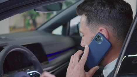hombre de negocios hablando en móvil mientras elige un coche en el salón