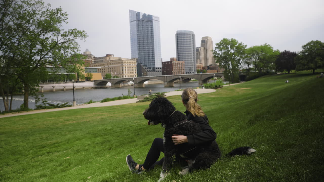 그녀의 개와 함께 도시 공원에서 앉아있는 젊은 여성의  ⁇ 드헬드  ⁇
