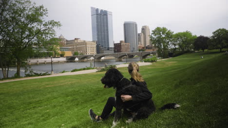 disparo de mano de una mujer joven sentada en un parque de la ciudad con su perro