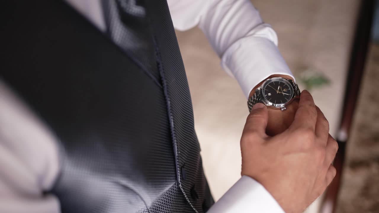 Groom in formal attire adjusts silver wristwatch with anticipation