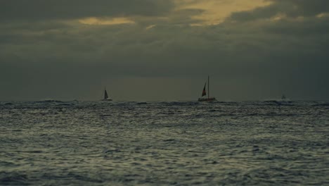 sailboats line the horizon as as a numinous stormy sky lines the backdrop near diamond head hawaii