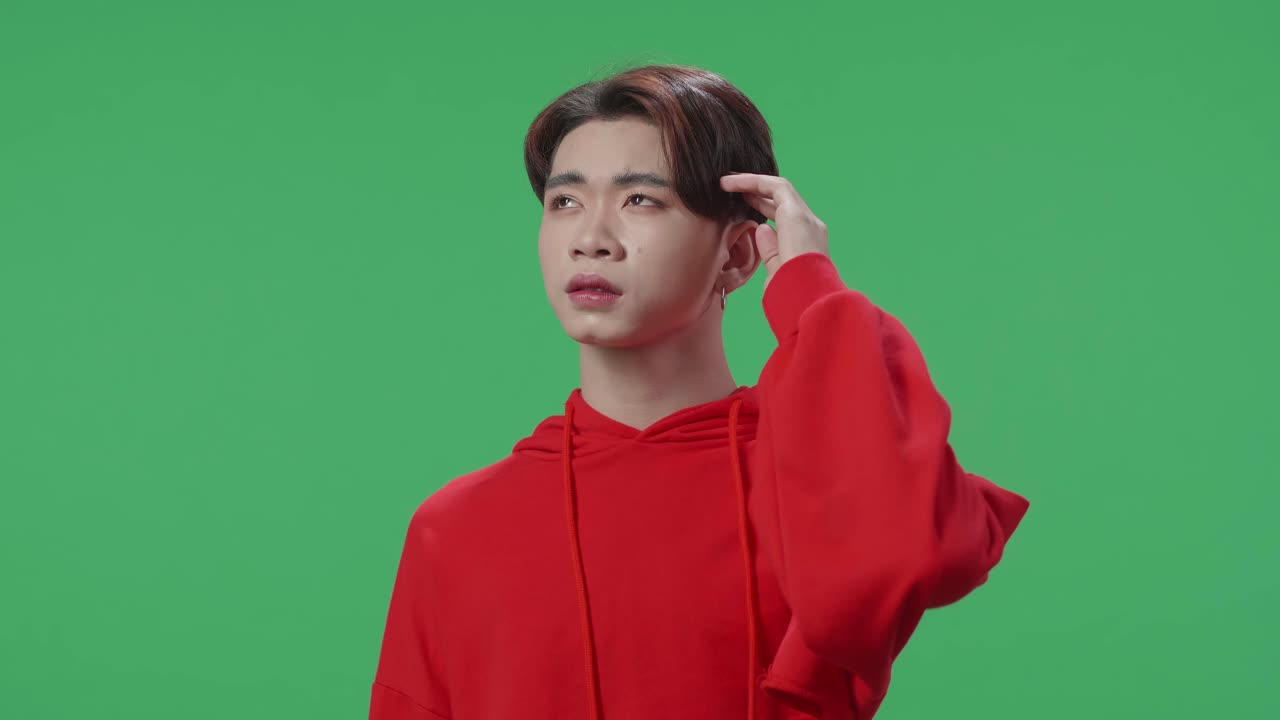 Young Asian Transgender Male Thinking About Something And Looking Around Then Raising Her Index Finger And Eyes Wide Open While Standing On Green Screen In The Studio