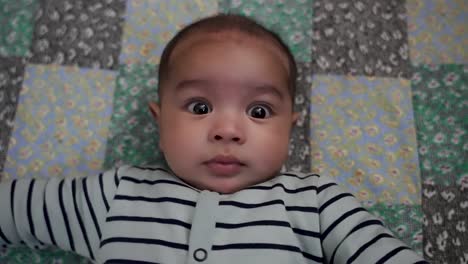 Overhead-View-Of-Adorable-4-Month-Old-Indian-Baby-Boy-Laying-On-Mat-Looking-At-Camera