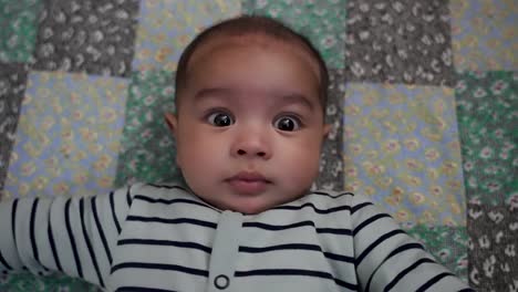 overhead view of adorable 4 month old indian baby boy laying on mat looking at camera