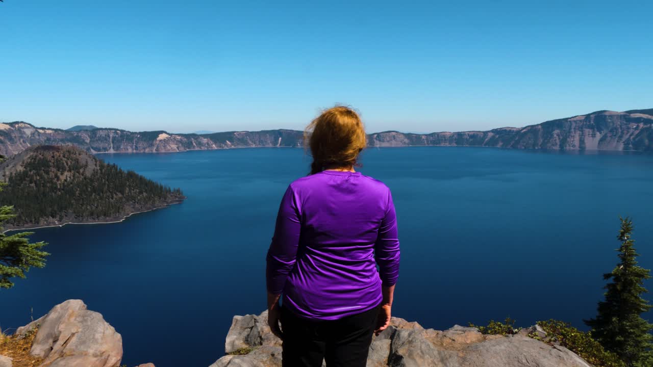 cabeza roja con una camisa morada se encuentra en el borde del parque nacional del lago del cráter