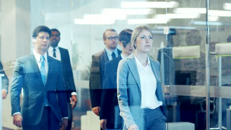 diverse team of delegates/ lawyers led by woman confidently marches through the corporate building hallway. multicultural crowd of resolute business people in stylish marble and glass offices.