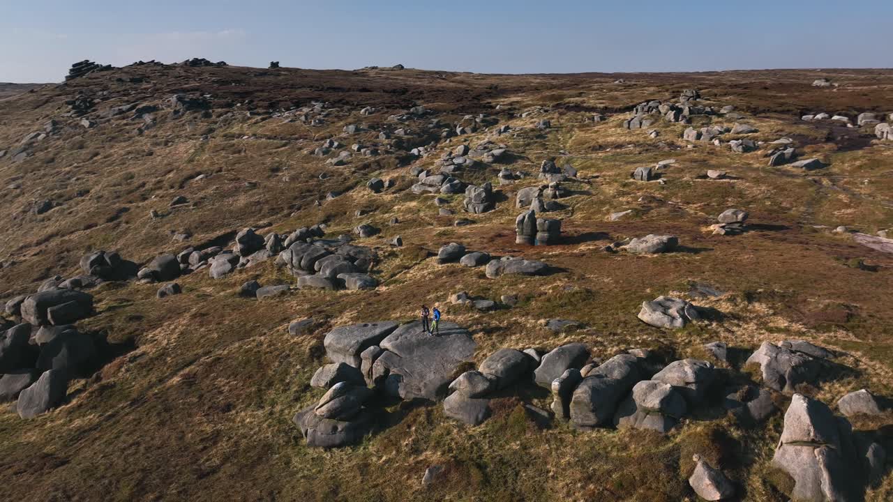 To vandrere stod i et stort klippefelt i en storslået dal på en solrig dag.