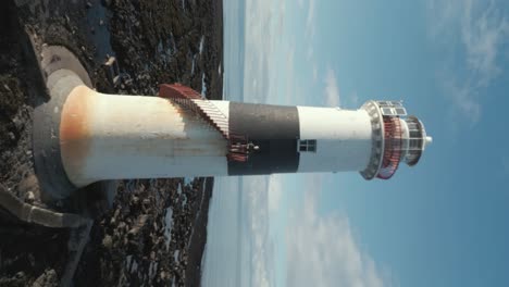 young man standing on lighthouse dynamic drone reveal shot