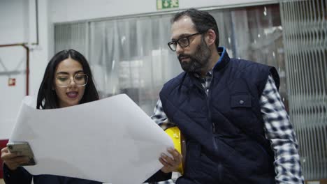 trabajadores de la fábrica enfocados hablando mientras caminan con el plano