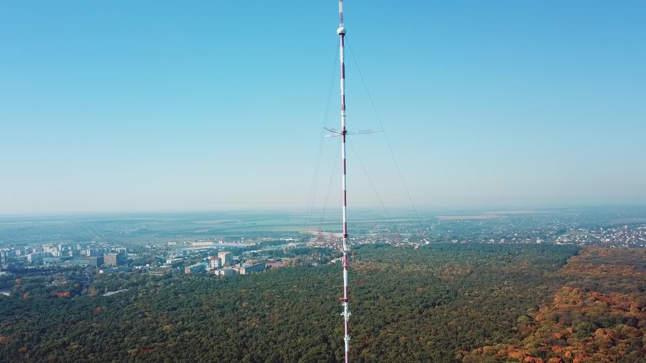 telecommunication antenna for television and radio broadcasting is located outside the city near the forest. Camera motion to left
