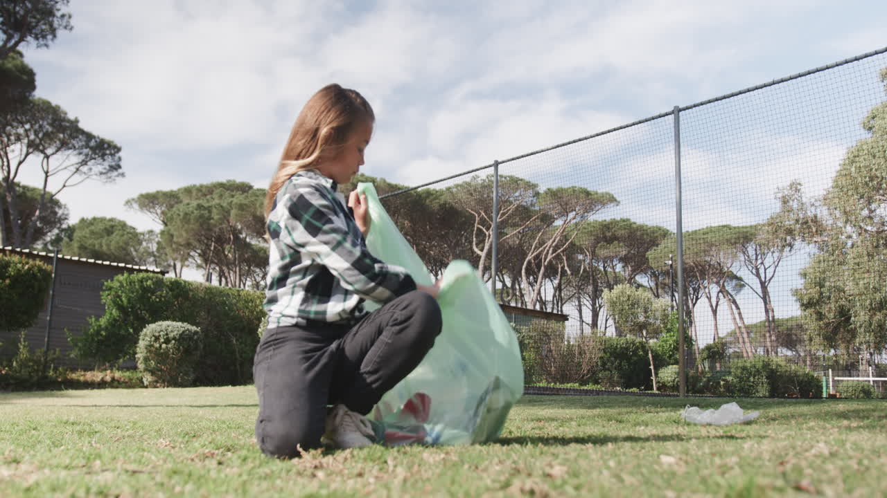 Girl picking up trash in park, promoting environmental awareness and cleanliness