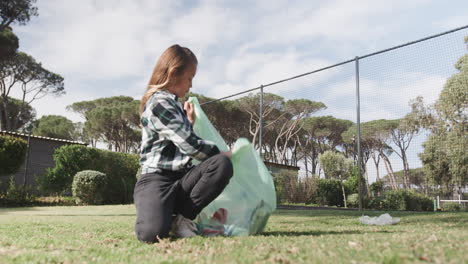 girl picking up trash in park, promoting environmental awareness and cleanliness