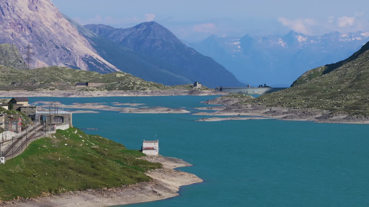 Alpine lake framed by rugged mountains under a bright sky, serene and scenic