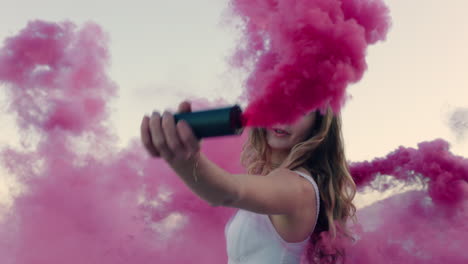 beautiful woman waving pink smoke bomb dancing on beach at sunrise celebrating creative freedom