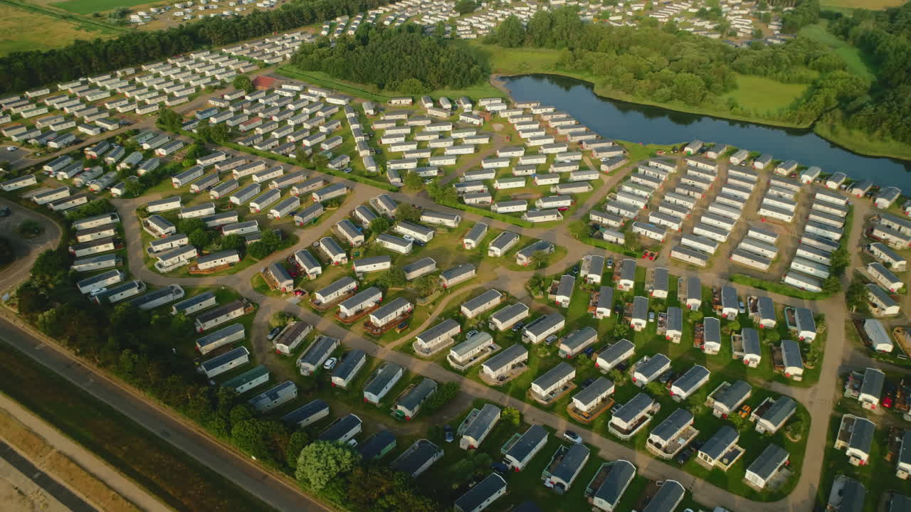 Establishing Drone Shot of Static Caravan Holiday Home Park with Small Lake and Trees on Sunny Day in North Norfolk UK East Coast
