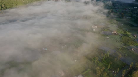 Mount-Batur-Caldera-filled-with-mist-during-morning-sunrise,-aerial