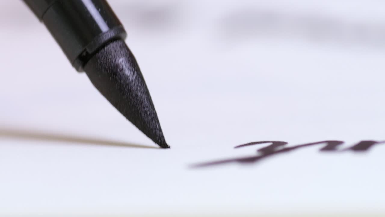 A close-up view of a black ink pen gracefully capturing the art of writing paper