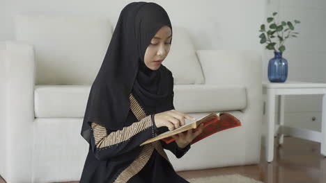 an asian muslim woman reciting salah or salat al-fatiha passage of the qur'an, in a single act of sujud called a sajdah or prostrations at home