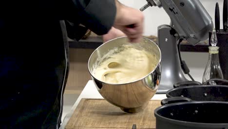 a chef prepares a delicious cake batter, using a stainless steel bowl. mixing ingredients thoroughly, the kitchen is filled with the aroma of baking. a relaxed atmosphere prevails.