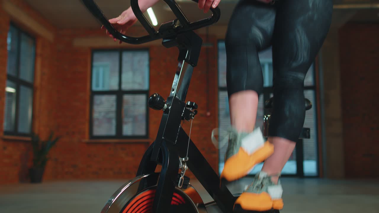 Woman performs aerobic endurance training workout cardio routine on the simulators cycle training