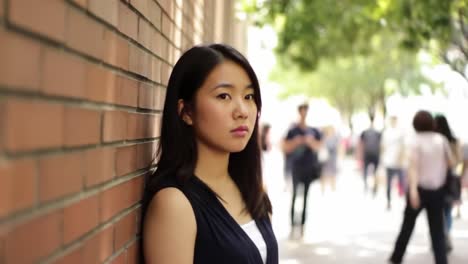 young woman standing beside a brick wall in the city
