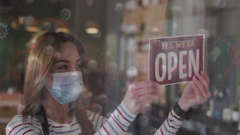 animation of coronavirus cells over caucasian female hairdresser closing salon wearing face mask