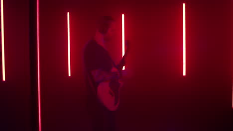 musician playing guitar in neon blue studio