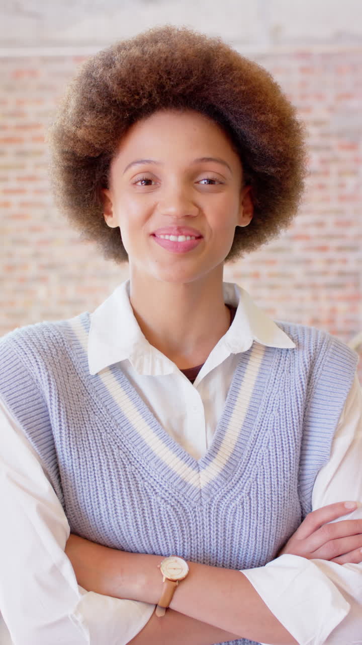 Vertical video portrait of happy biracial businesswoman smiling in office, slow motion