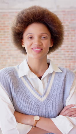vertical video portrait of happy biracial businesswoman smiling in office, slow motion