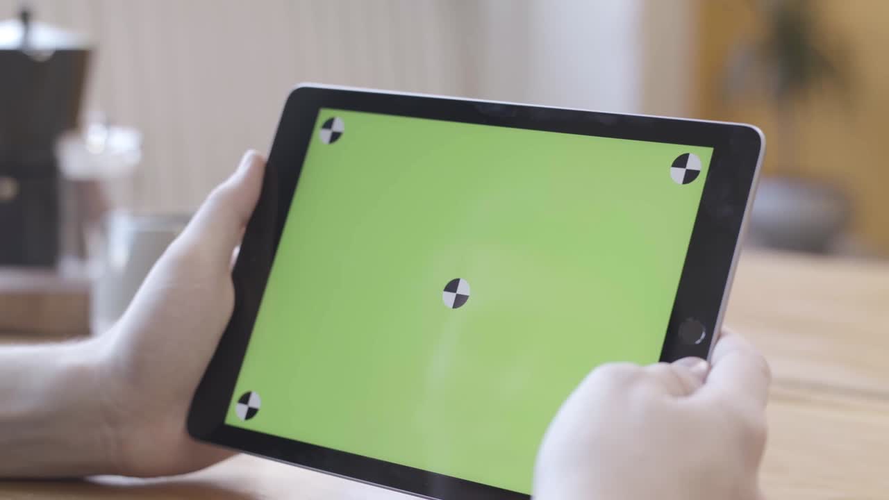 persona que sostiene una tableta con una pantalla verde