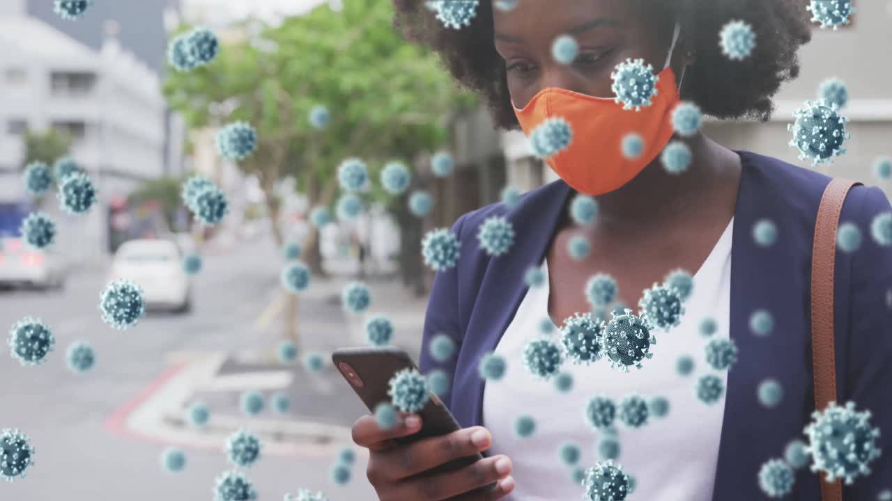 animación de células de covid 19 sobre una mujer afroamericana con máscara facial usando un teléfono inteligente