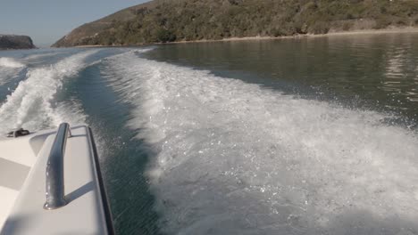 pov rear and side wake from speed boat motoring along sunny shore