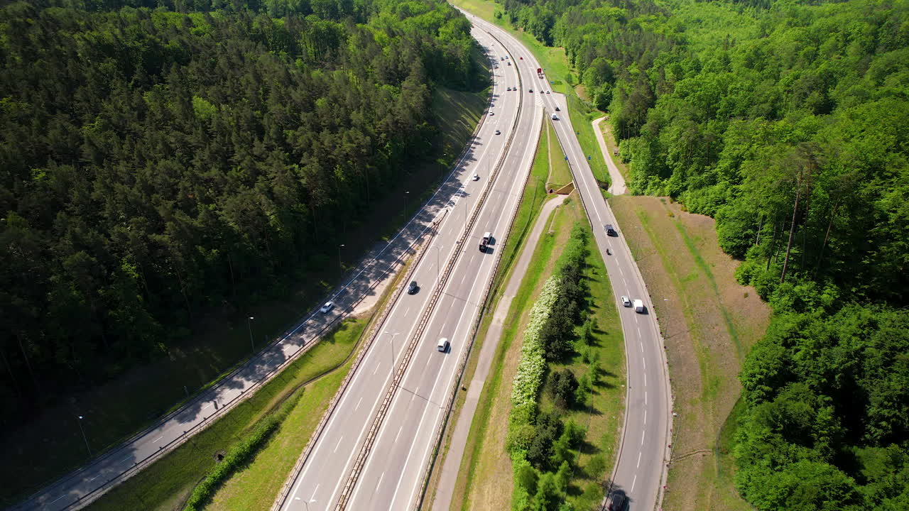 tiro de ojo de pájaros de drones que muestra el tráfico en la carretera asfaltada rodeada de bosques verdes y densos
